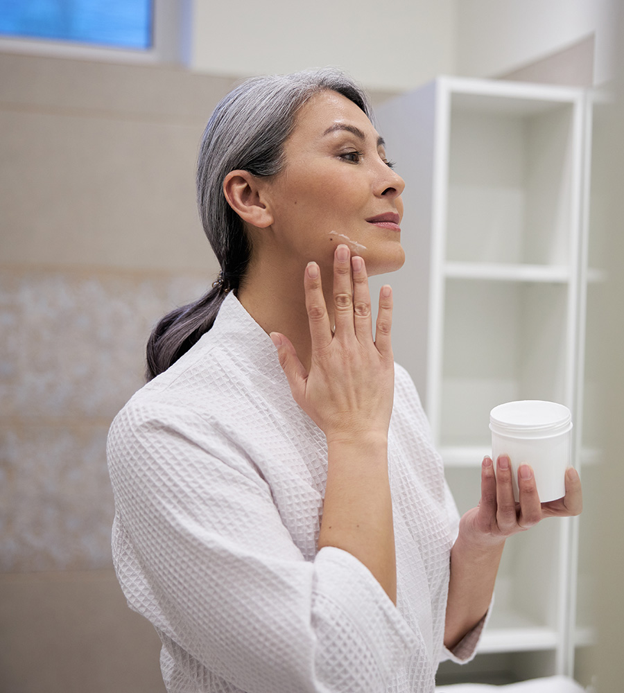 Mature woman applying cream to her face