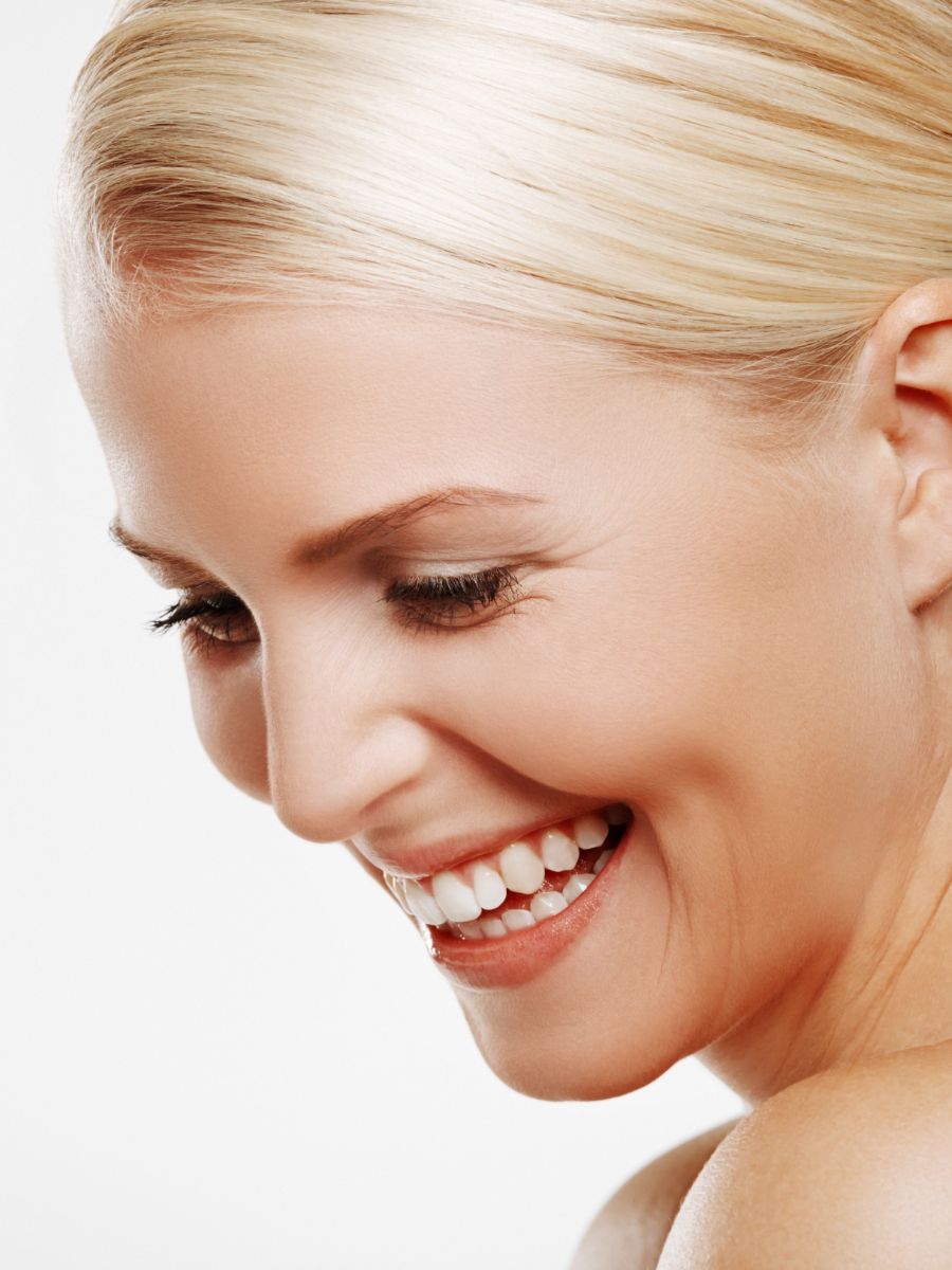 blond woman against a studio white backgorund smiling