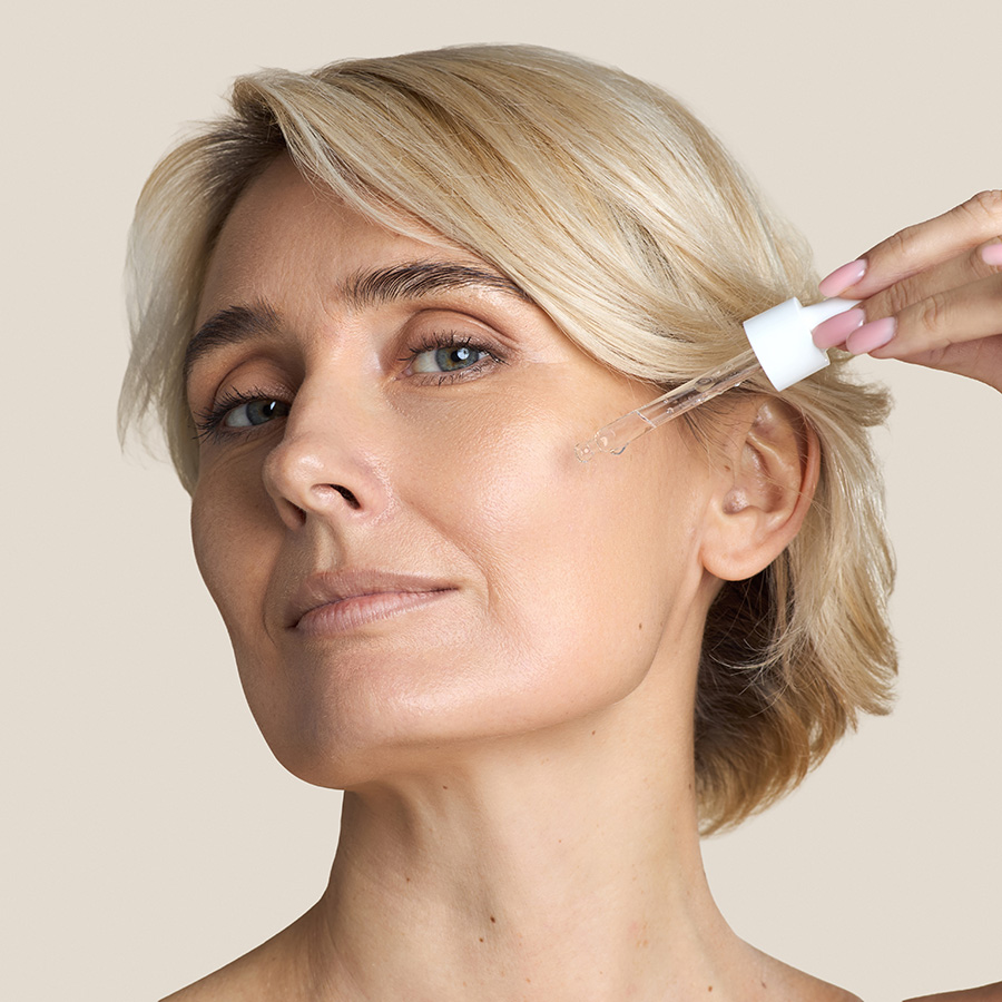 Mature woman putting an oil on her face