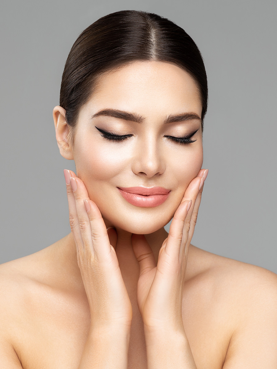 Woman with dark hair touching her cheeks