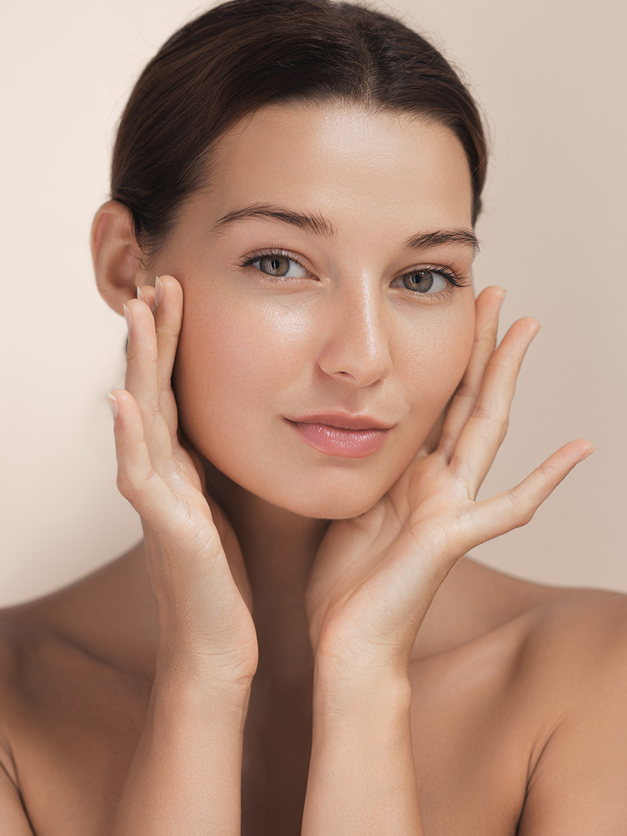 young woman with glowing skin touching her face