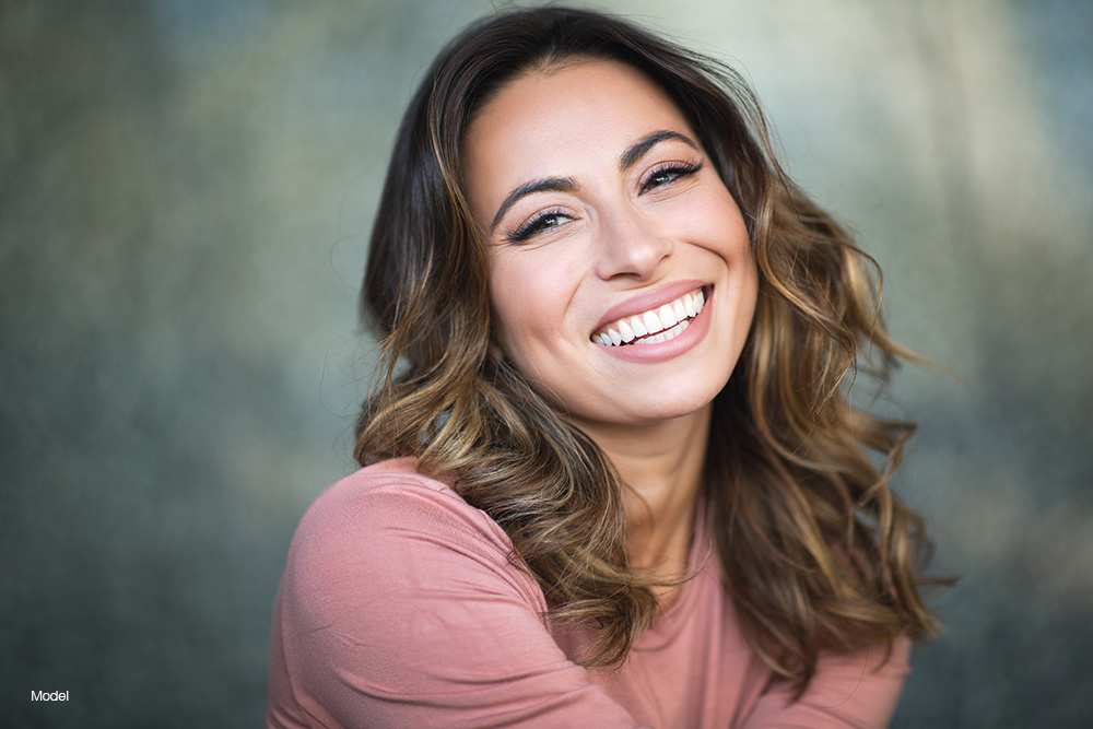 Mature woman with curly brown hair in a pink shirt